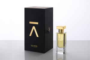 Studio photograph of a ‘Naked Forest’ perfume bottle by Azman Perfumes in collaboration with Prin Lomros, set against a white background. The bottle reflects a green, veggie, and mysterious aesthetic, highlighting elements such as iris, sandalwood, and mango.