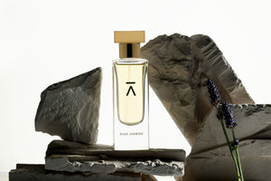 Studio photograph of a ‘Naked Forest’ perfume bottle by Azman Perfumes in collaboration with Prin Lomros, set against a white background. The bottle reflects a green, veggie, and mysterious aesthetic, highlighting elements such as iris, sandalwood, and mango.